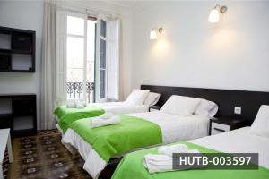 a hotel room with three beds with green sheets at Big Apartment Barcelona Gran via in Barcelona