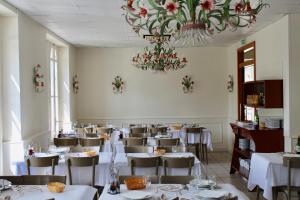 a dining room with white tables and chairs and a chandelier at Hôtel Sainte Marie in Lourdes