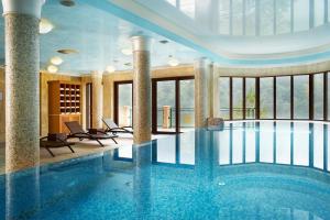 a large swimming pool in a building with a large window at Retro Riverside Wellness Resort in Karlovy Vary
