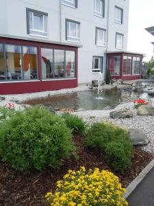 a building with a pond in front of a building at Allgäuhotel Memmingen Nord in Memmingen