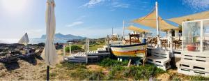 un bateau assis dans le sable à côté d'un bâtiment dans l'établissement U'Cuntu affittacamere, à Favignana