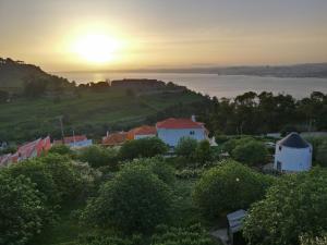 un villaggio con il sole che tramonta sull'acqua di Olá Belém! Cozy Windmill, Stunning views to Lisboa a Caparica