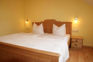 a bedroom with a large bed with white sheets and pillows at Ferienwohnungen im Haus Bi Henny in Baabe