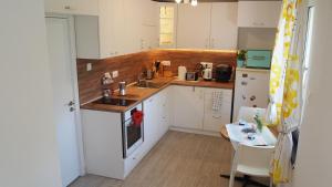 a kitchen with white cabinets and a sink and a table at Villa Burkopolis in Sozopol