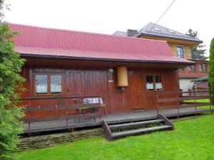 een grote houten hut met een rood dak bij Tanie Spanie in Wysowa-Zdrój