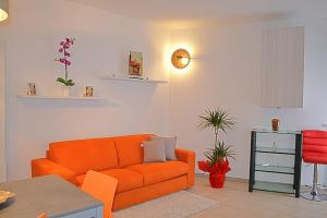 Cabà Holiday Bardolino Gritti في باردولينو: غرفة معيشة مع أريكة برتقالية وطاولة