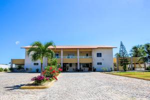 um grande edifício branco com uma palmeira e flores em Pousada Itarema Residence em Itarema