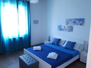 a blue bedroom with a large bed with blue curtains at Mondello Sicily Rooms in Mondello
