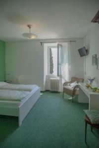 a bedroom with a bed and a chair and a window at Prà de la Fam B&B in Tignale