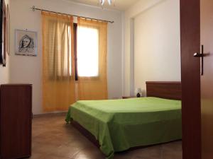 a bedroom with a green bed and a window at Casa Irene in San Vito lo Capo