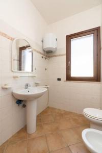 een badkamer met een wastafel, een toilet en een spiegel bij Casa Irene in San Vito lo Capo