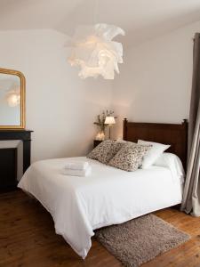 a bedroom with a white bed and a mirror at Il Etait Une Fois Chez Moi - La Maison De Tante Marie in Le Loroux-Bottereau