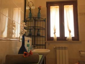 baño con lavabo y jarrones en un estante en La Sirenetta, en Passoscuro