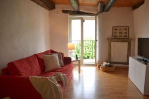 un soggiorno con divano rosso e TV di Casa la Finestra sul Lago - WelcHome a Cannobio