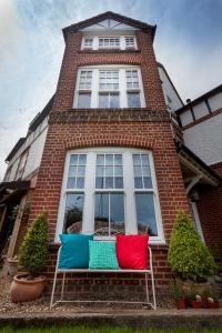 two colorful pillows sitting on a bench in front of a house at Corner House Bed & Breakfast in West Runton