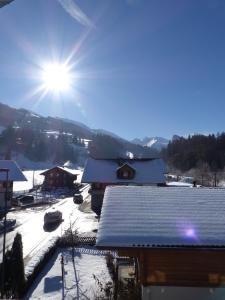 uma casa coberta de neve com o sol no céu em Gasthof Hirschen em Oey