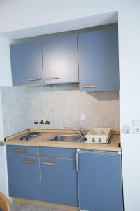Susanna Apartments في كيراموتي: مطبخ مع دواليب زرقاء ومغسلة