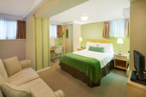 a hotel room with a bed and a tv at Victoria's Mansion Guest House in Toronto