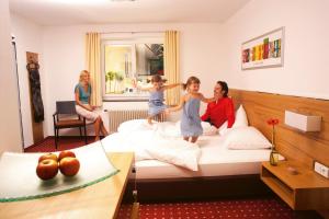 a woman and two children jumping on a bed at Hotel.Pension.Golingen in Golling an der Salzach
