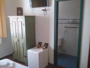 a small kitchen with a refrigerator and a microwave at Pousada Vovô Chiquinho in Tiradentes