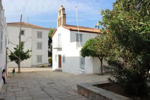 a white building with a steeple and a child standing in front at Studio Annezo in Hydra