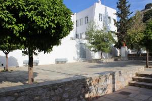 a white building with a tree and a stone wall at Studio Annezo in Hydra