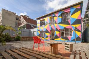 a red chair sitting in front of a building with a mural at Social Hostel Café e Bar in Curitiba