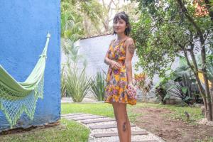a woman in a dress standing next to a blue wall at Social Hostel Café e Bar in Curitiba