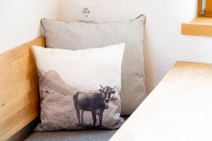 a pillow with a cow standing next to a bed at Apartment Buchsteiner in Haus im Ennstal