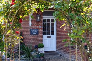 a brick house with a white door and a sign at Corner House Bed & Breakfast in West Runton