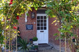 a brick house with a white door and a sign at Corner House Bed & Breakfast in West Runton +12 photos