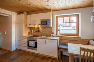 cocina con armarios blancos, fregadero y ventana en Apartment Buchsteiner, en Haus im Ennstal