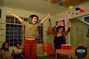 a woman is standing with her arms in the air at Social Hostel Café e Bar in Curitiba
