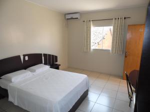 - une chambre avec un lit blanc et une fenêtre dans l'établissement Mosaico Hotel, à Dianópolis