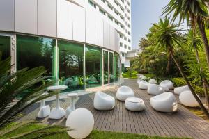 a row of white chairs and tables in front of a building at HF Ipanema Park in Porto