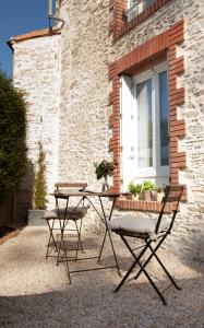 una mesa y dos sillas frente a una ventana en Il Etait Une Fois Chez Moi - La Maison De Tante Marie, en Le Loroux-Bottereau