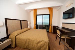 a bedroom with a bed and a desk and a television at Hotel Joli in San Marino