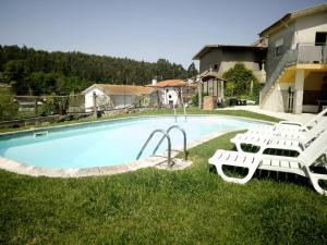 a swimming pool with two lawn chairs at Vivenda Mendes in Outeiro