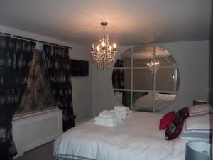 a bedroom with a bed with a mirror and a chandelier at Hewlett Apartments in Cheltenham