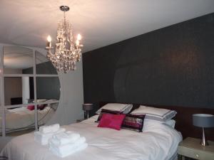 a bedroom with a large white bed with a chandelier at Hewlett Apartments in Cheltenham