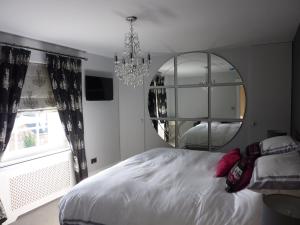 a bedroom with a large bed and a mirror at Hewlett Apartments in Cheltenham