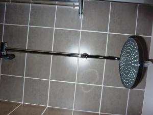 a shower with a strainer on a tiled wall at Hewlett Apartments in Cheltenham