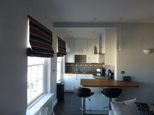 a kitchen with a counter and two stools at Hewlett Apartments in Cheltenham