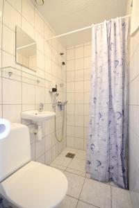 Baño blanco con cortina de ducha y aseo en Aisa Guesthouse en Pärnu