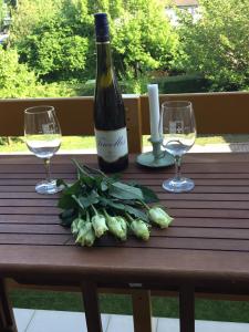 a bottle of wine and two glasses on a wooden table at Soós Apartman in Balatonfüred