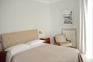 a bedroom with a white bed and a chair at Vacanze Murgiane in Altamura