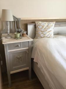 a bed with a side table with a lamp on it at Soós Apartman in Balatonfüred