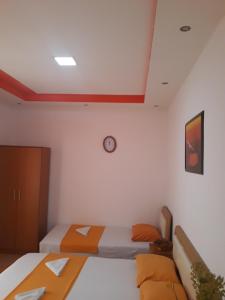 a bedroom with two beds and a clock on the wall at Apartments Aza in Dobra Voda