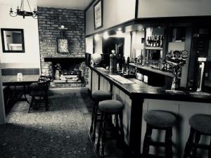 a bar with stools in a room with a fireplace at The Cross Keys Hotel in Llanymynech
