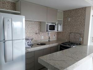 a kitchen with a white refrigerator and a stove at Flat Kariris Home Service in Juazeiro do Norte